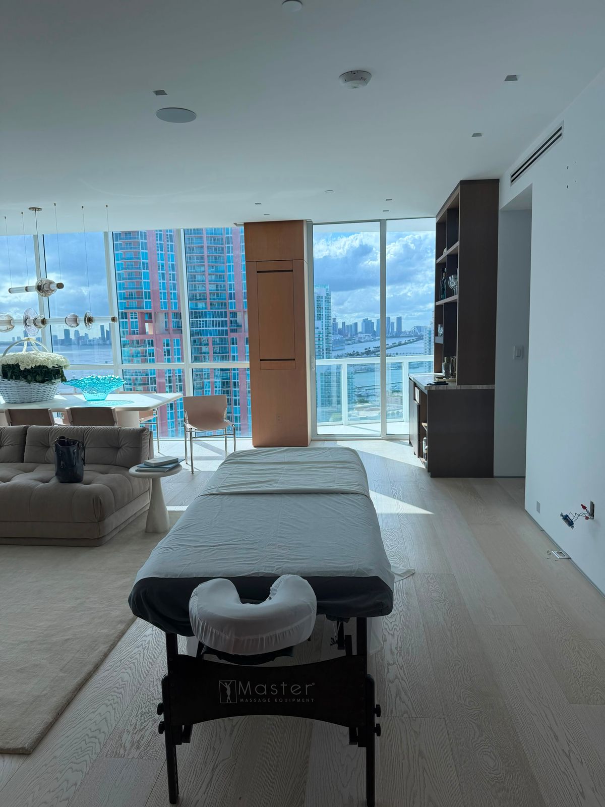 Massage table set up in a sunlit Miami condo living room with bay views