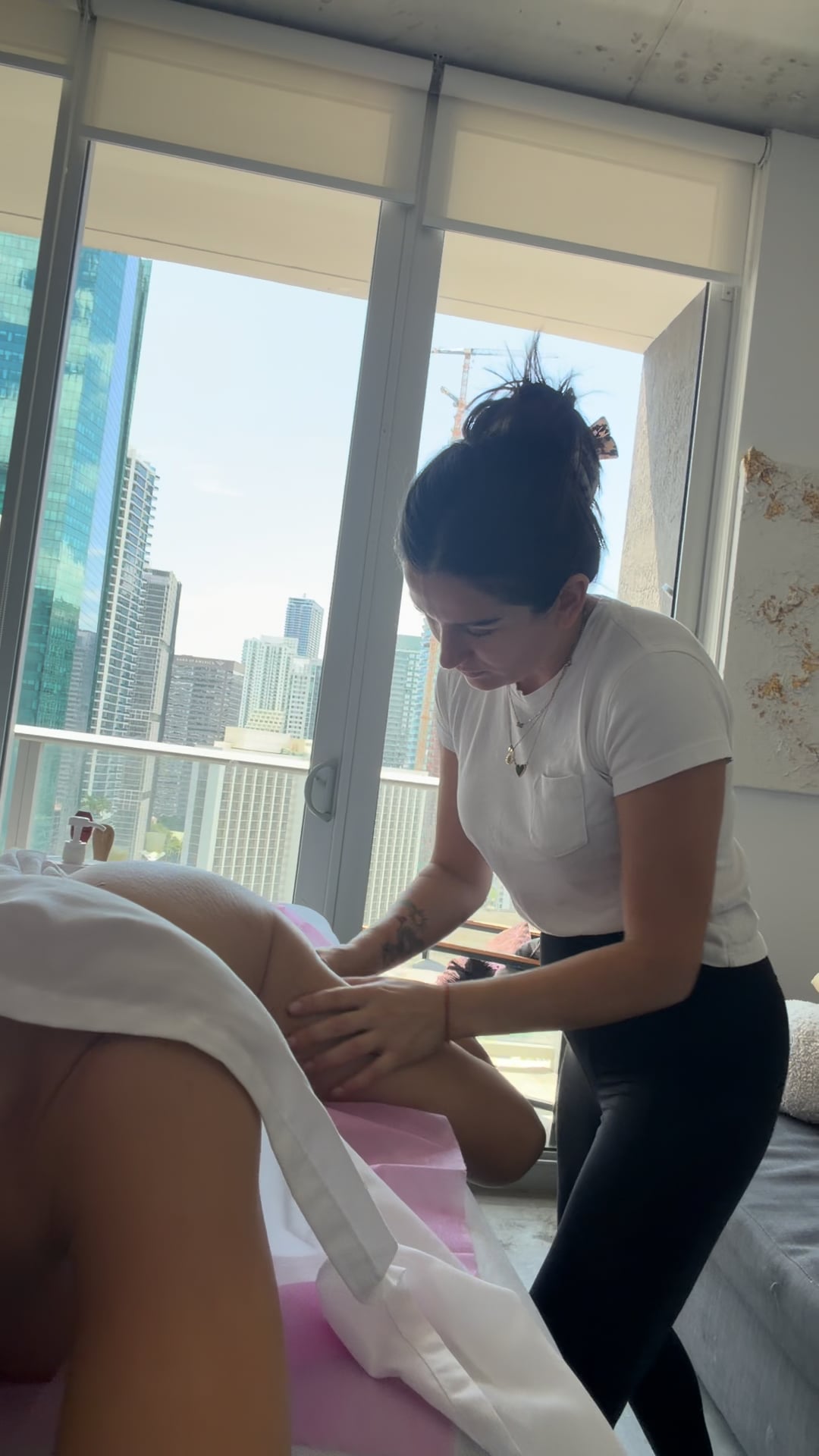Elisa working on a client at a massage table set up in a Miami home